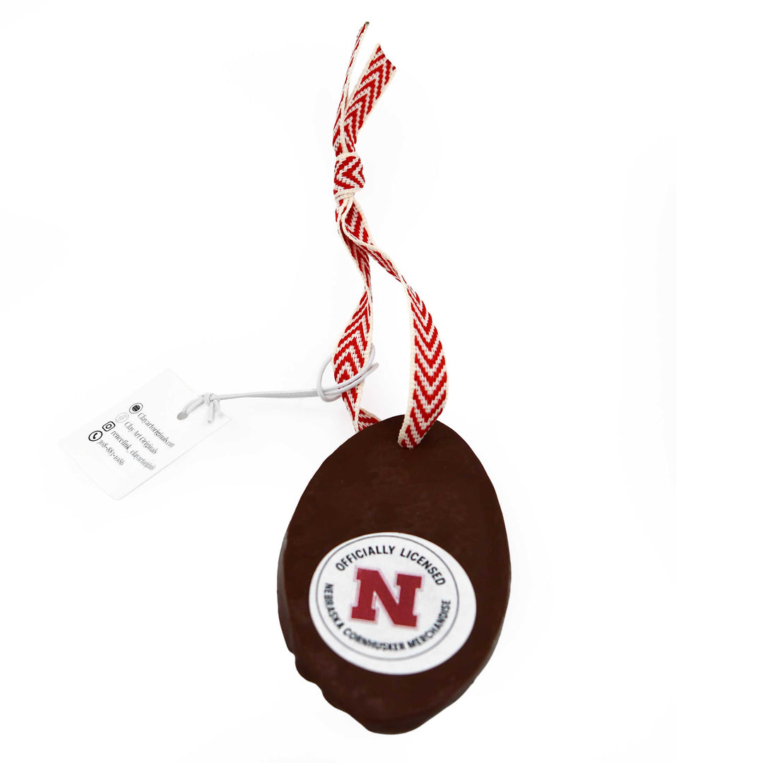 Brown football-shaped ornament with a red and white logo on a white background