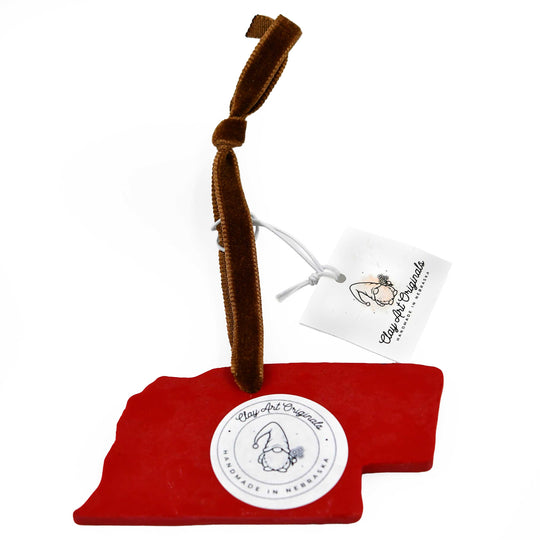 Back of Nebraska-shaped ornament with a heart and 'Home' text, attached to a brown ribbon with a tag.background