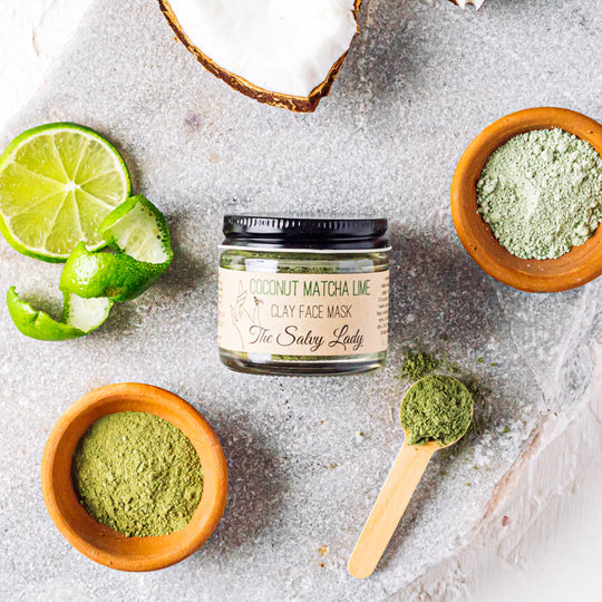 Jar of coconut matcha lime clay face mask with ingredients on a textured surface