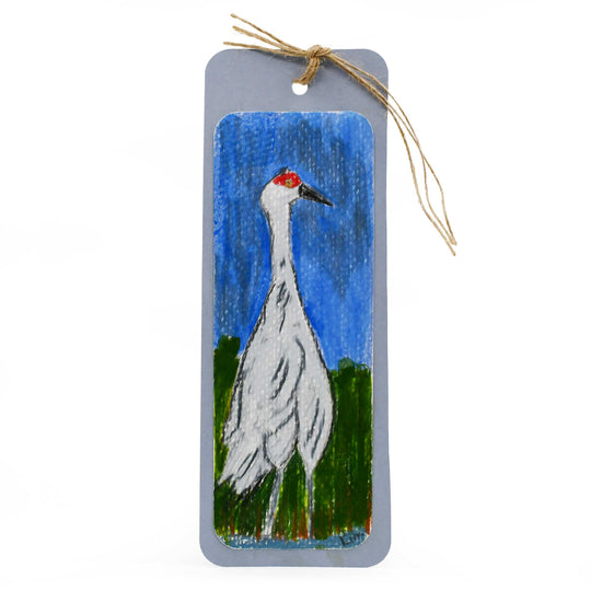 Painted wooden tag with a crane illustration on a blue background