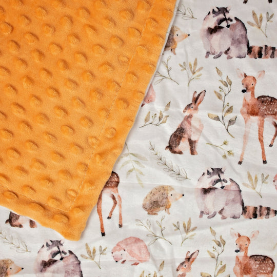 Orange textured blanket next to a white blanket with forest animal patterns