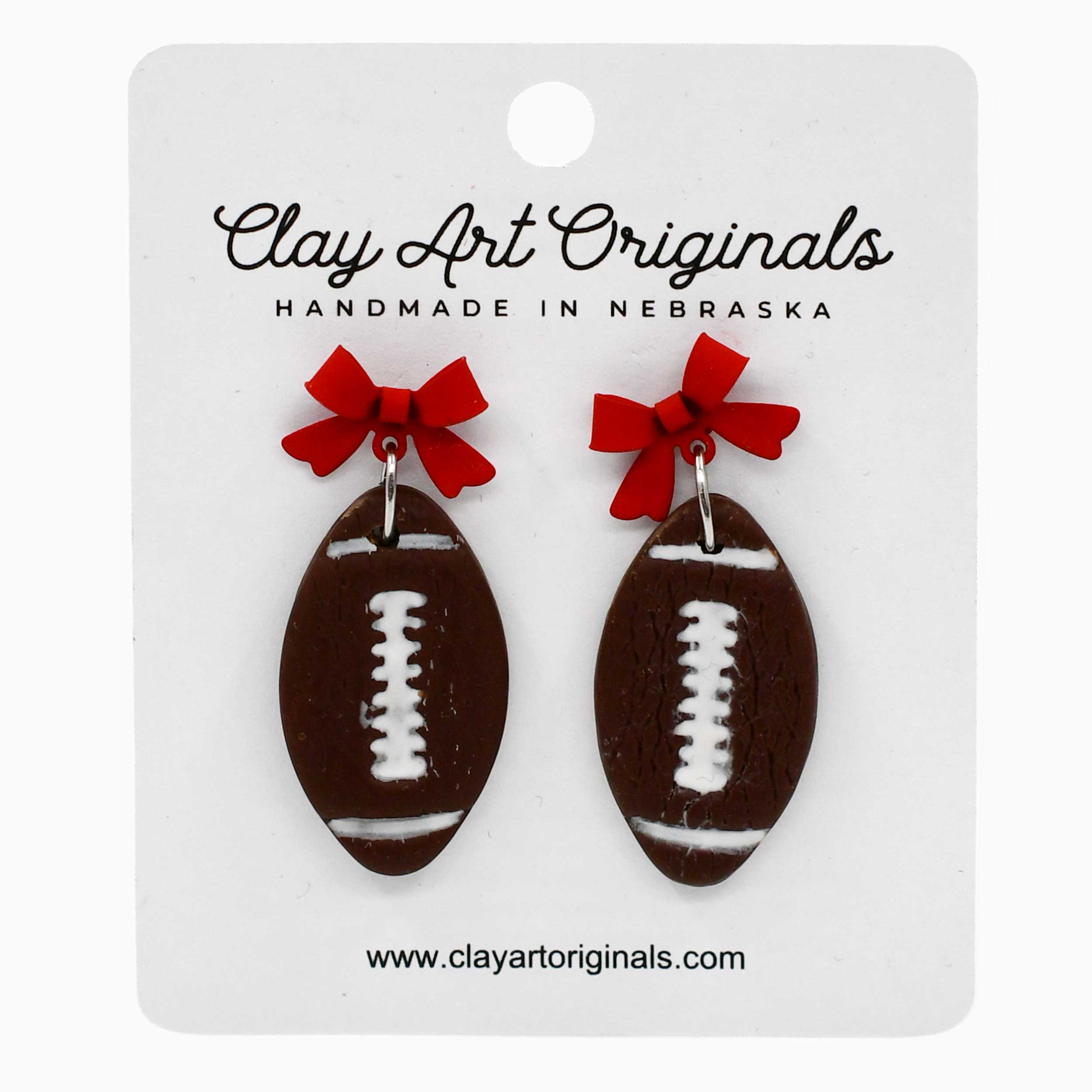 Football-shaped earrings with red bows on a Clay Art Originals card.