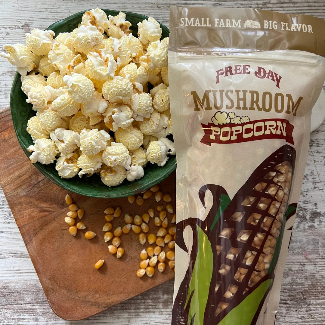 Mushroom popcorn in a bowl with a package labeled 'Free Day Mushroom Popcorn' on a wooden surface.