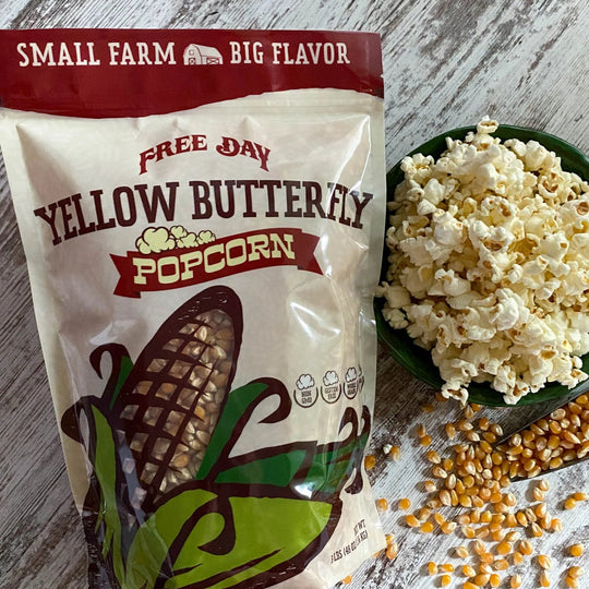 Bag of Free Day Yellow Butterfly Popcorn with popcorn and kernels on a wooden surface