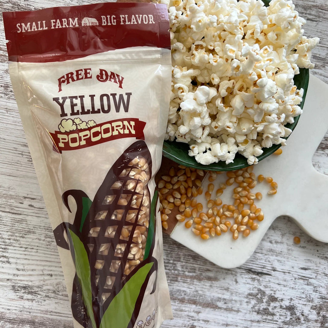 Free Day Yellow Popcorn bag with popcorn and kernels on a wooden surface