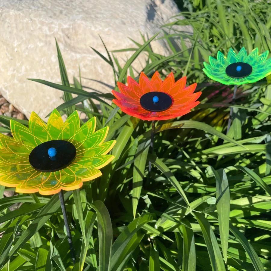 A three pack of glowing sunflowers in grass. Colors: Green, Pink, and Yellow