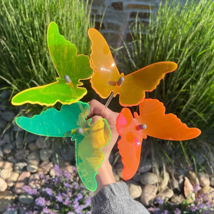 A four pack of glowing butterflies with someone holding them like a bouquet. Colors: Orange, Pink, Green, Yellow
