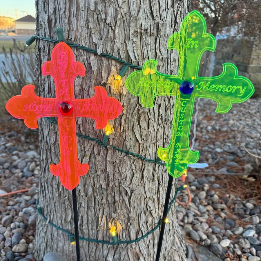 Glowing "In Loving Memory" and "Faith, Hope, Love, Joy" crosses in front of a tree