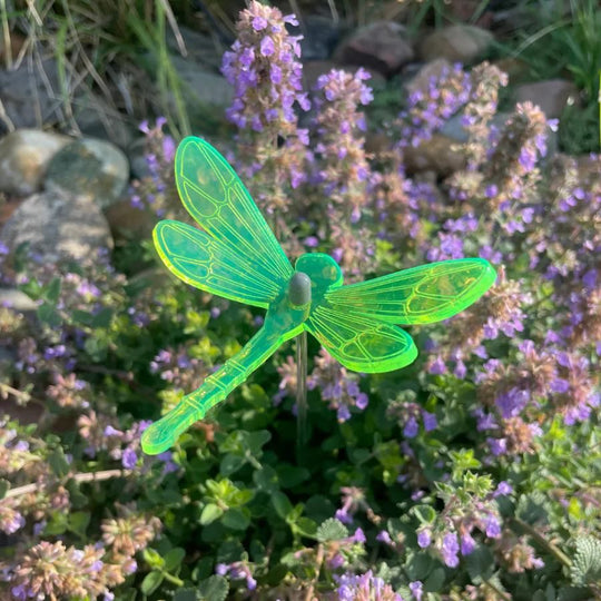 A green glowing dragonfly in flowers