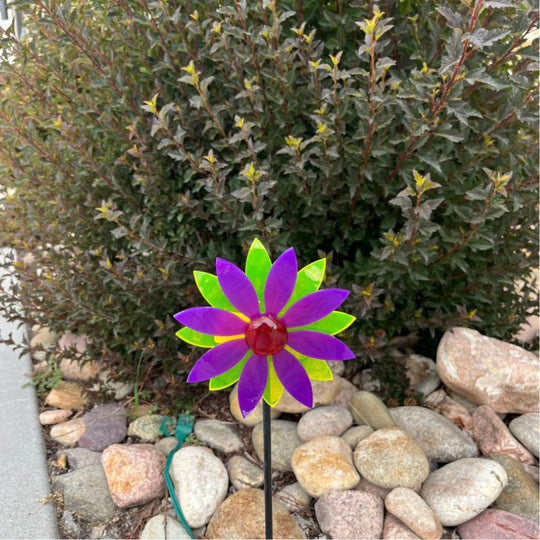 A glowing purple and yellow pinwheel against a bush