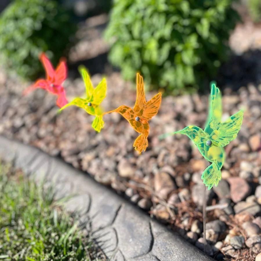 A four pack of glowing hummingbirds in rocks. Colors: Pink, Yellow, Orange, and Green