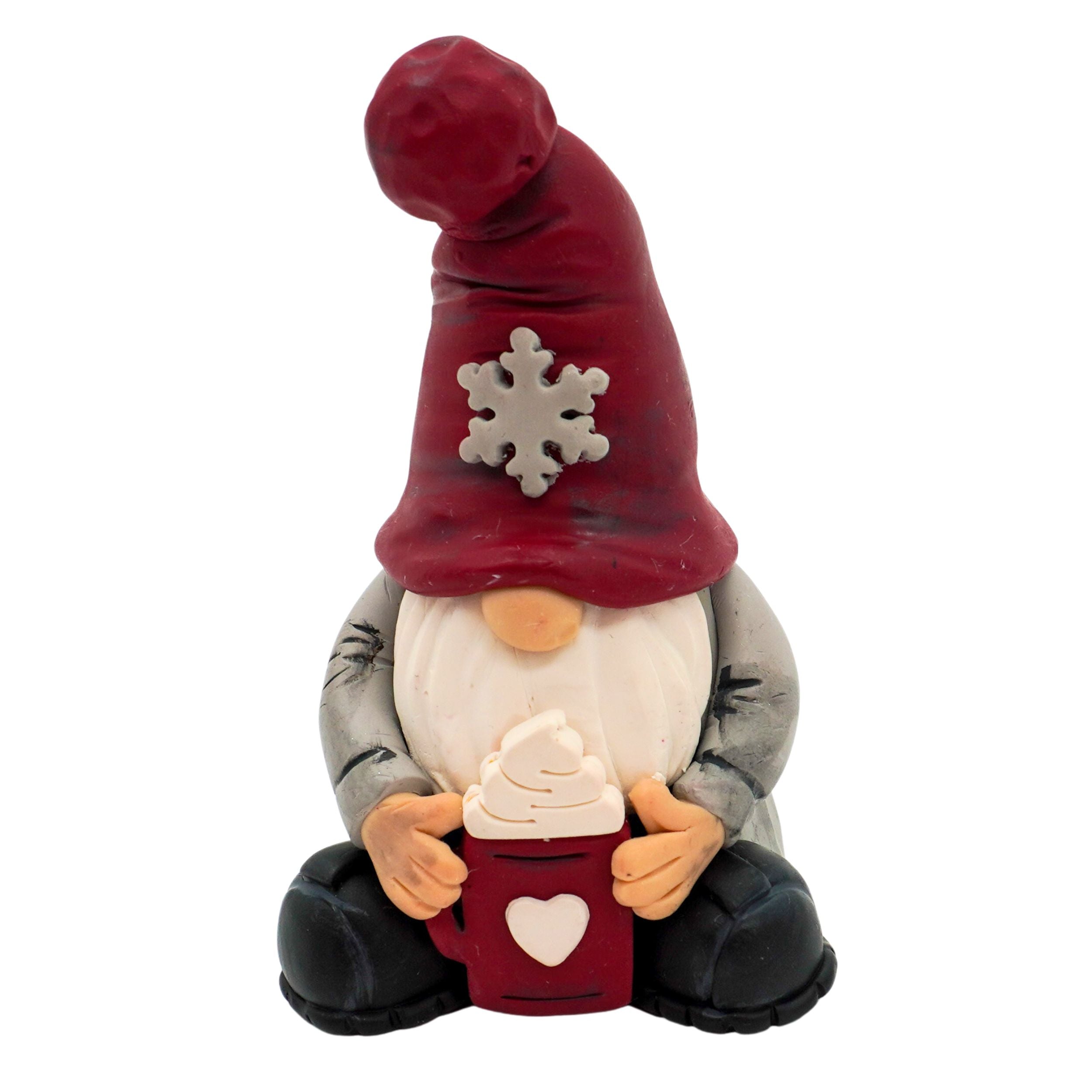 Gnome figurine with a red hat featuring a snowflake, holding a mug with a heart on a white background.