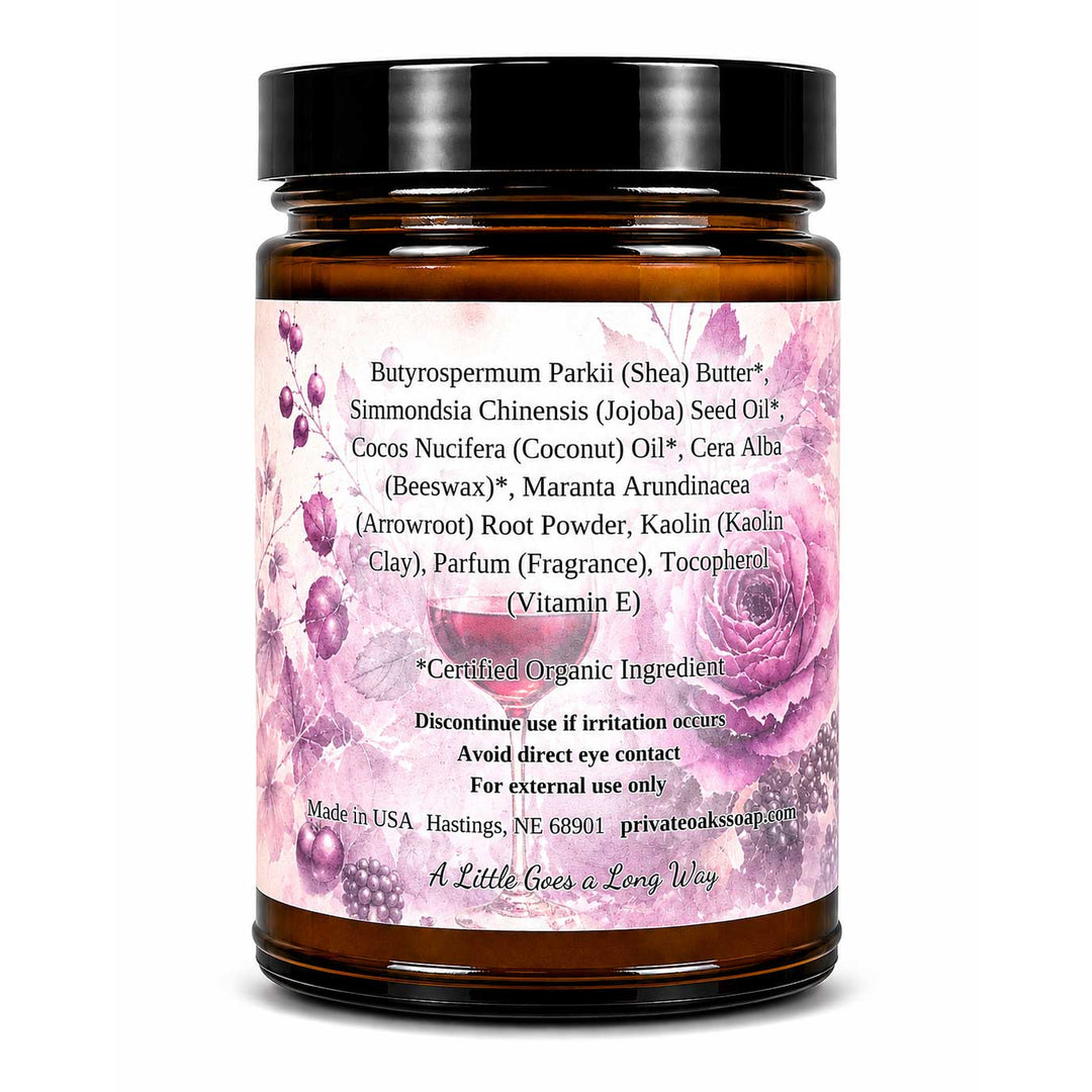 An amber glass jar with a black lid and a pink floral label, photographed on a plain white background. The label contains product ingredients and usage text.