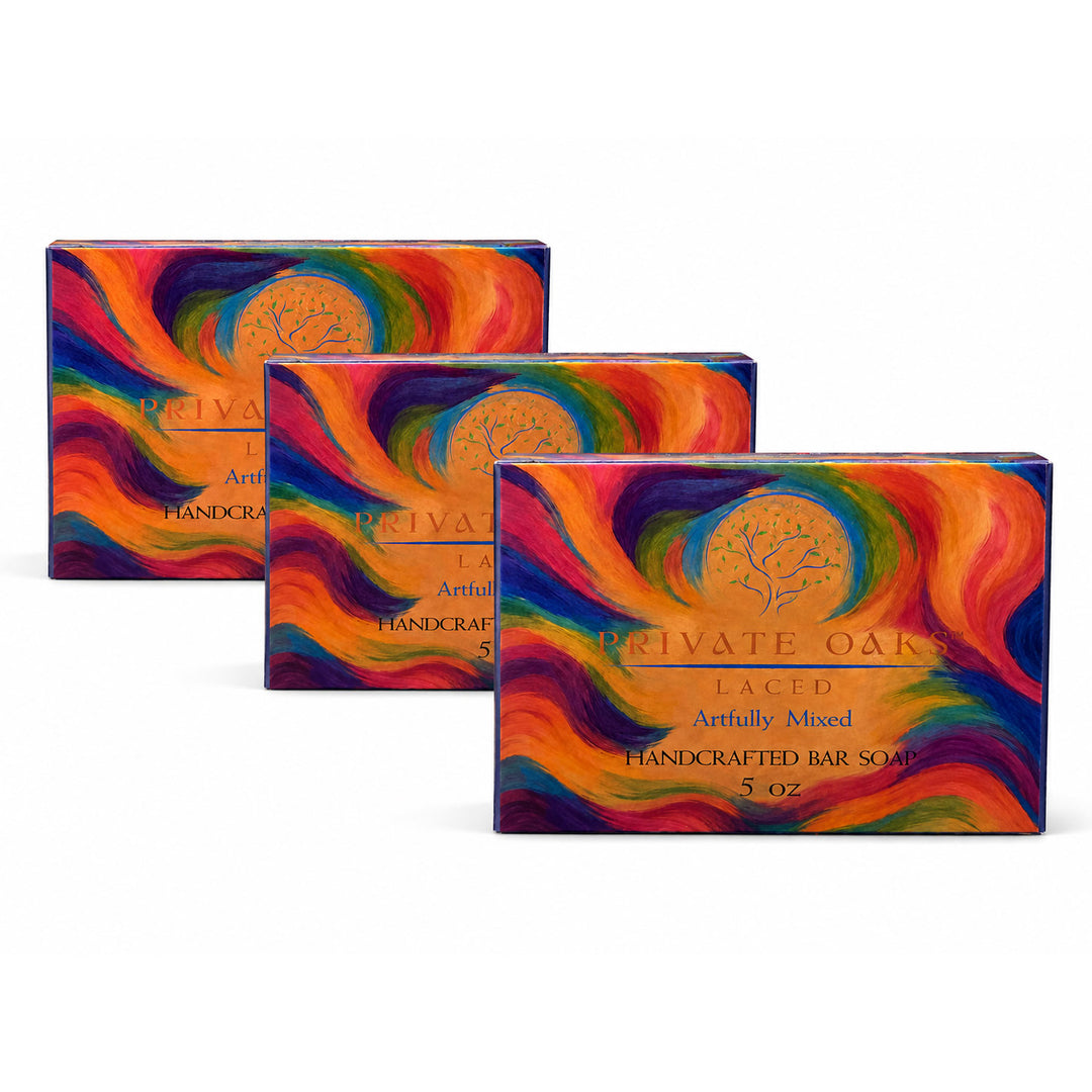 Three boxes of Private Oaks Laced Artfully Mixed Handcrafted Bar Soap arranged in a staggered row on a white background. The packaging features a vibrant, multicolored swirl pattern of red, orange, yellow, green, blue, and purple with a gold circular tree logo in the center.