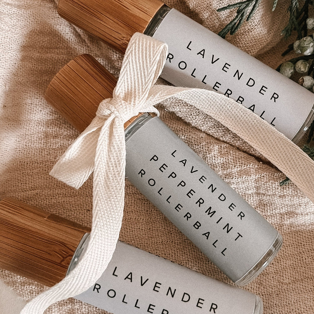 Lavender and lavender peppermint essential oil rollerball sitting on muslin with a ribbon bow