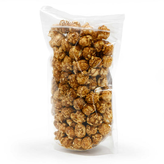 Clear bag filled with caramel popcorn on a white background