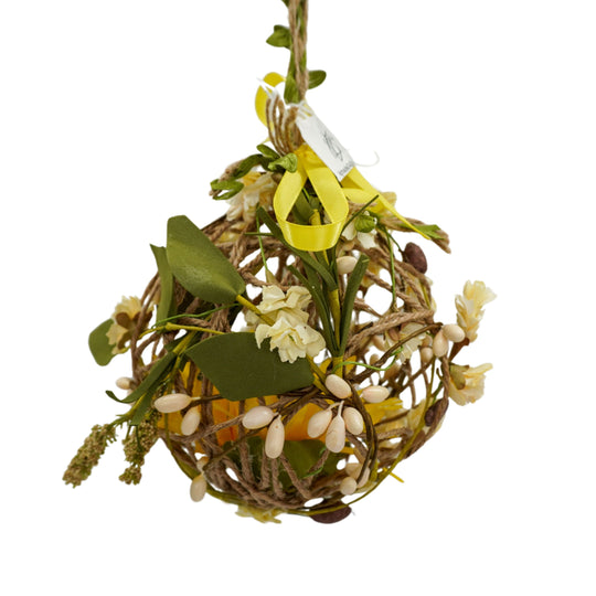 Decorative spherical ball with greenery and a yellow ribbon on a white background