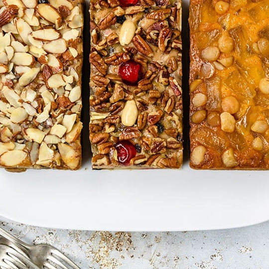 Three different types of cakes on a white plate with a light background.