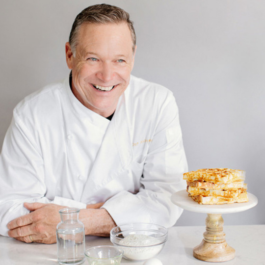 Portrait Of Heavenly Waffles CEO, Chef Bob, next to a stack of fresh waffles. 