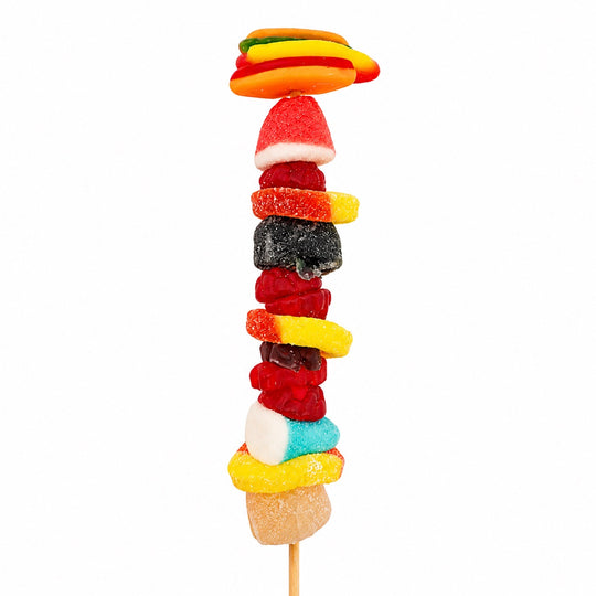 Hot dog candy kabob topped with a gummy hot dog and layered with assorted fruit-flavored gummy candies on a wooden skewer, isolated on a white background.