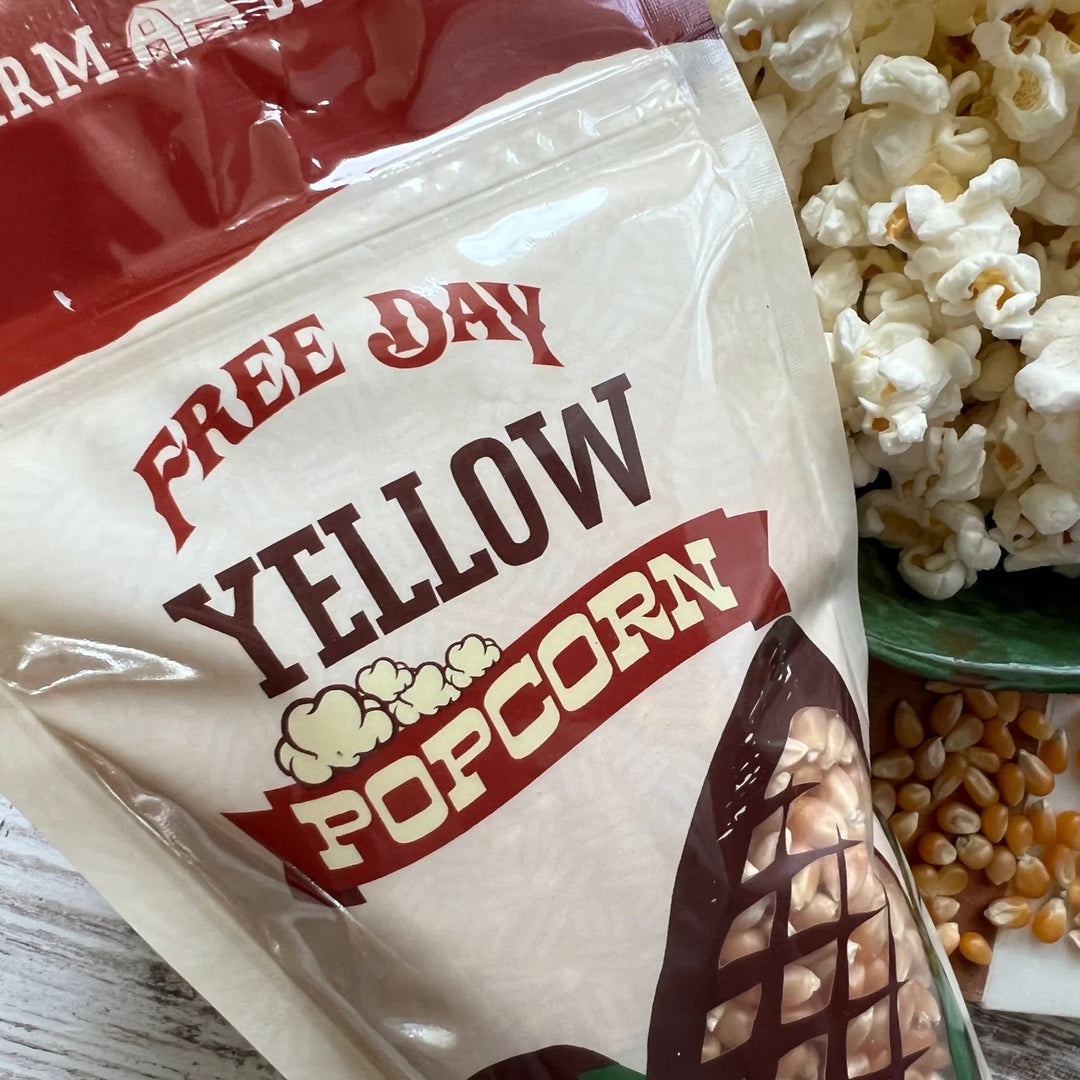 Bag of Free Day Yellow Popcorn with popcorn and kernels on a wooden surface