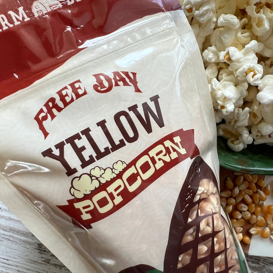 Bag of Free Day Yellow Popcorn with popcorn and kernels on a wooden surface