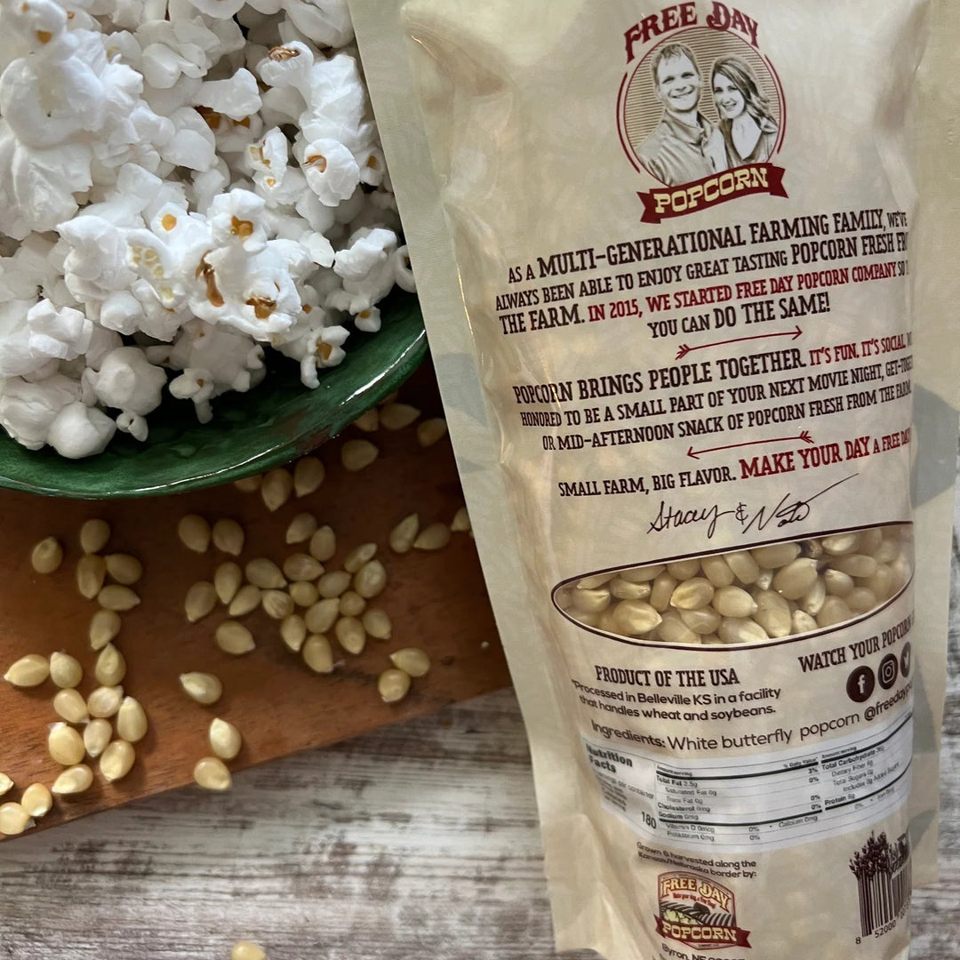 Popcorn kernel bag with text and a bowl of popcorn on a wooden surface