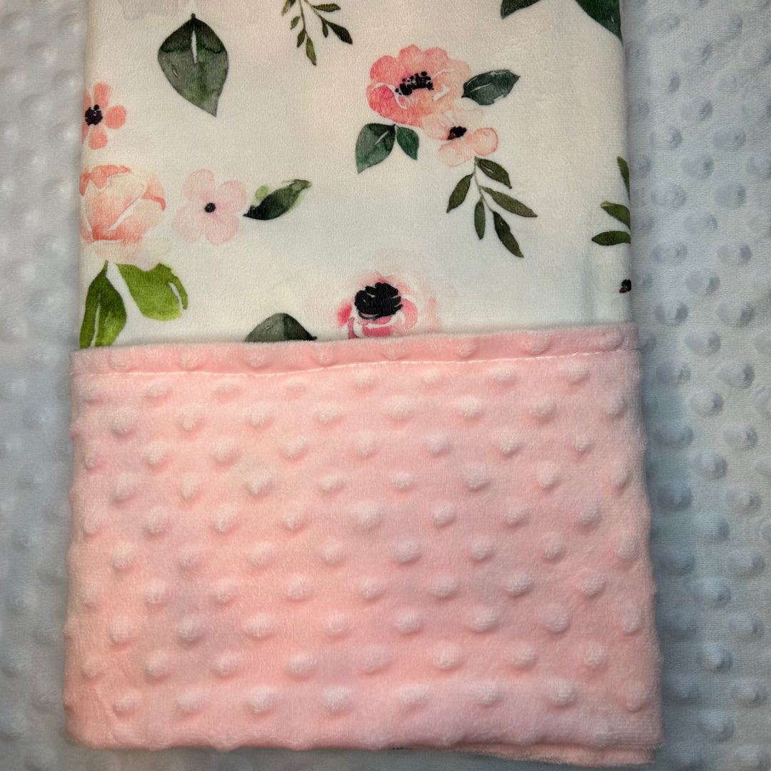 Floral patterned blanket with pink textured border on a textured surface