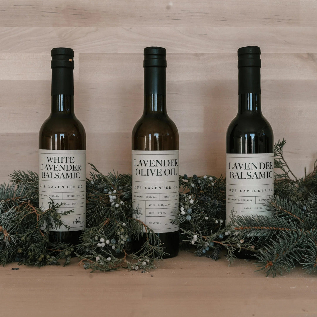 Three bottles of White Lavender products on a wooden surface with greenery.