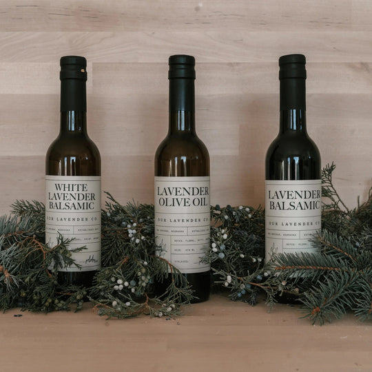 Three bottles of White Lavender products on a wooden surface with greenery.