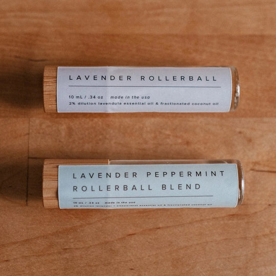 Lavender and lavender peppermint essential oil rollerballs sitting on a wood table