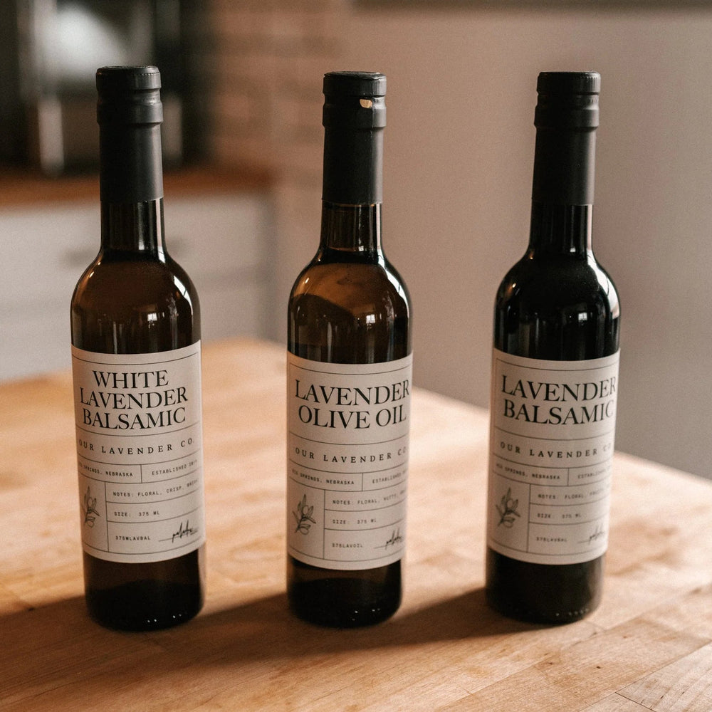 Three bottles of Lavender Balsamic on a wooden surface with a kitchen background.