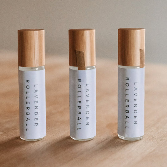 pack of 3 Lavender essential oil rollerball sitting on a wood table