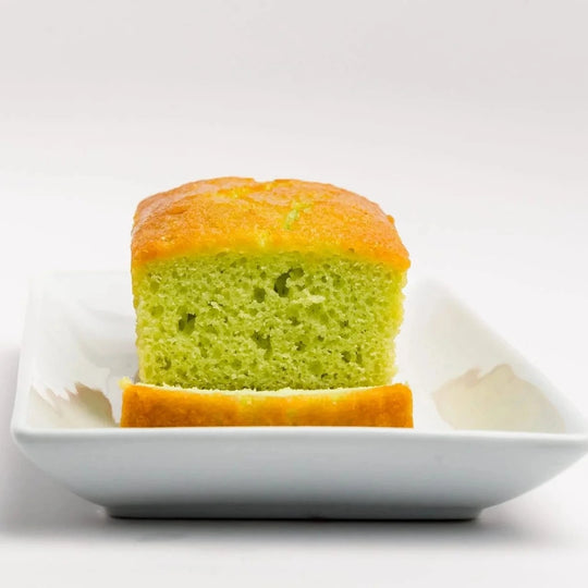 Green and orange cake on a white plate with a white background