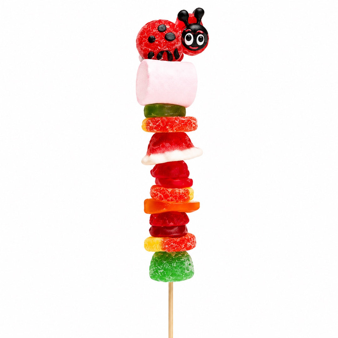 Ladybug candy kabob featuring a red and black ladybug gummy topper and assorted fruit-flavored candies on a wooden skewer, isolated on a white background.