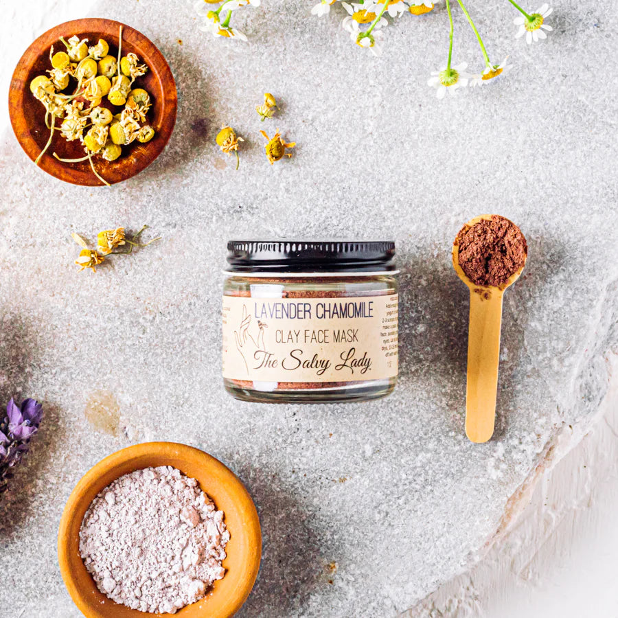 Clay face mask jar with ingredients on a textured surface