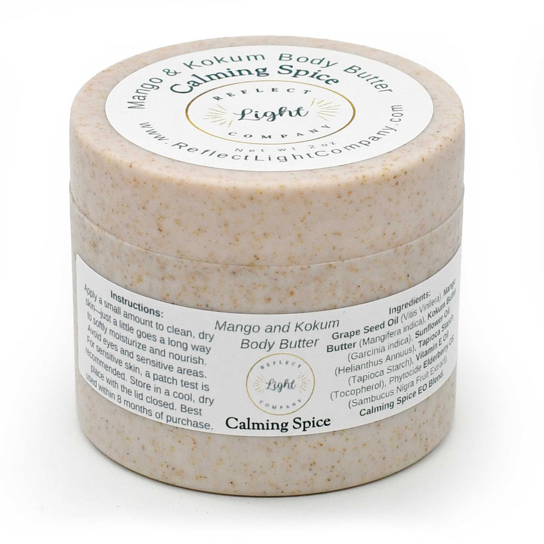A round jar of Mango and Kokum Body Butter with Calming Spice by Reflect Light Company, featuring a beige speckled texture and white labels.
