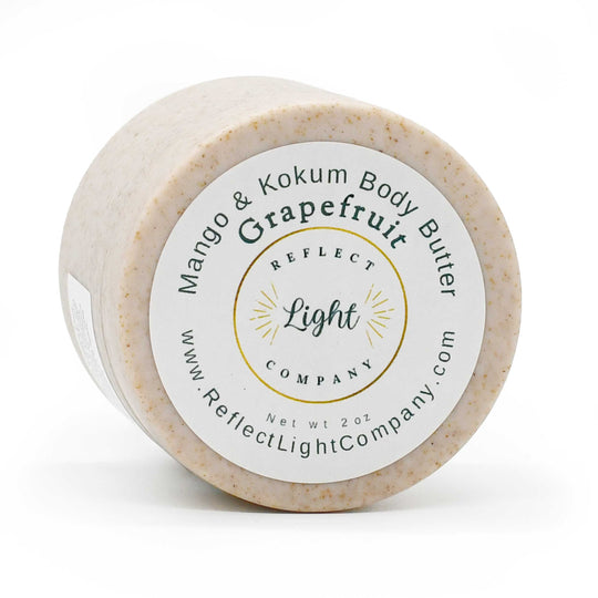 A 2 oz jar of Reflect Light Company Grapefruit & Kokum Body Butter, showing the textured beige product through the clear plastic container and its white circular label.
