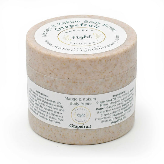 A round jar of Grapefruit Mango & Kokum Body Butter by Reflect Light Company, featuring a speckled beige product inside and white labels with black and gold text.
