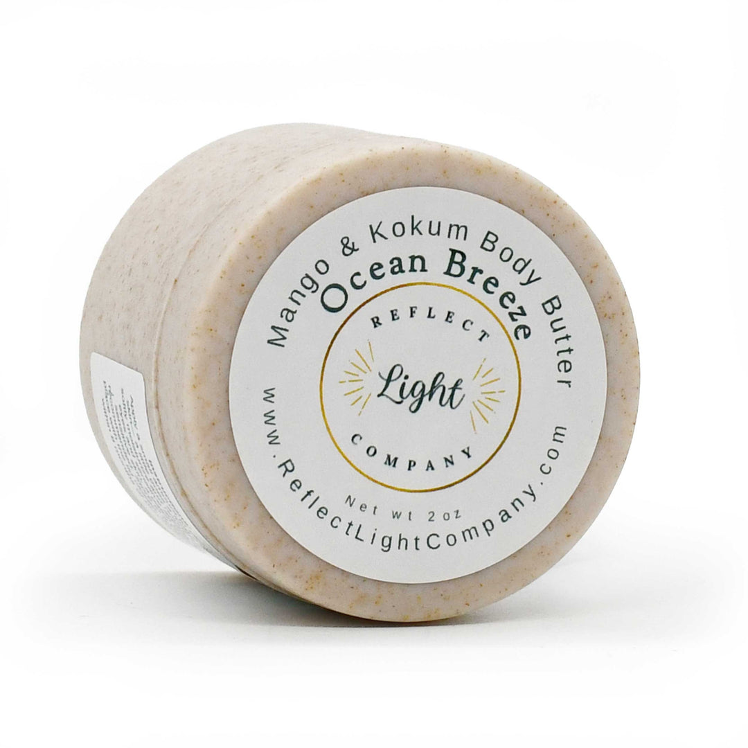 A round tub of Reflect Light Company Ocean Breeze Body Butter in the Mango & Kokum scent, featuring a white label with gold and black text on a clean white background.
