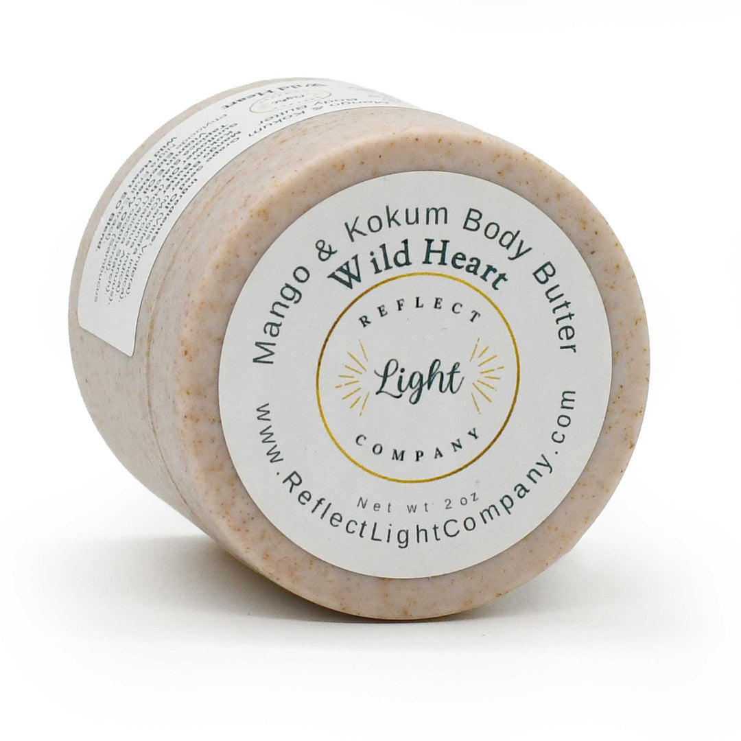 A 2 oz jar of Reflect Light Company Mango & Kokum Body Butter, featuring a light beige textured body butter inside a clear jar with a white and gold label.