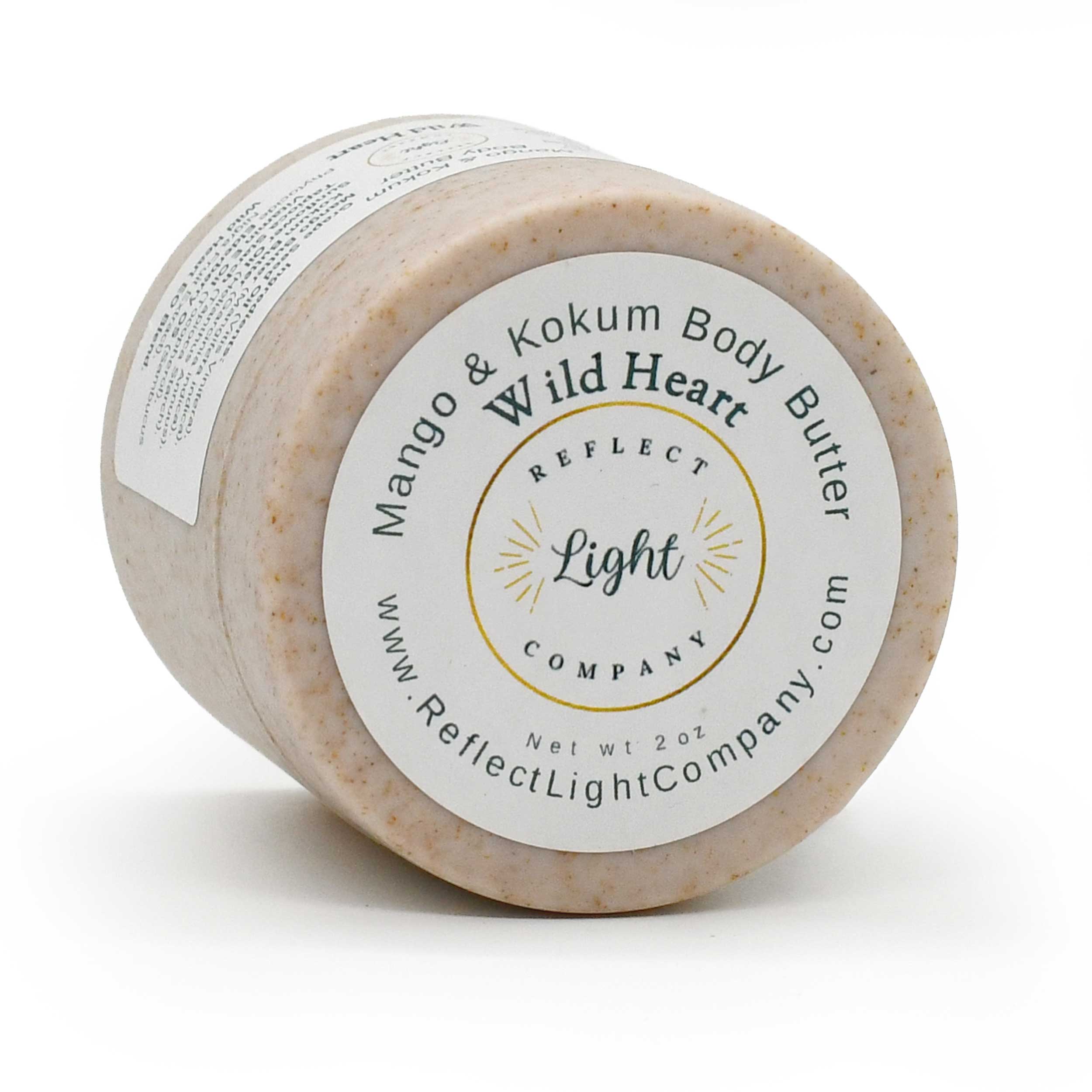 A 2 oz jar of Reflect Light Company Mango & Kokum Body Butter, featuring a light beige textured body butter inside a clear jar with a white and gold label.