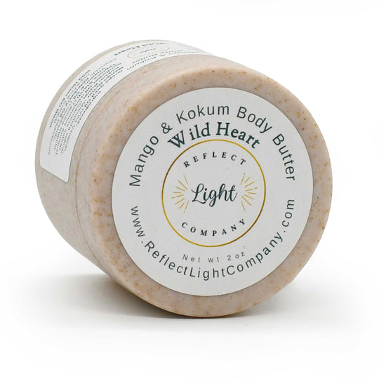A 2 oz jar of Reflect Light Company Mango & Kokum Body Butter, featuring a light beige textured body butter inside a clear jar with a white and gold label.