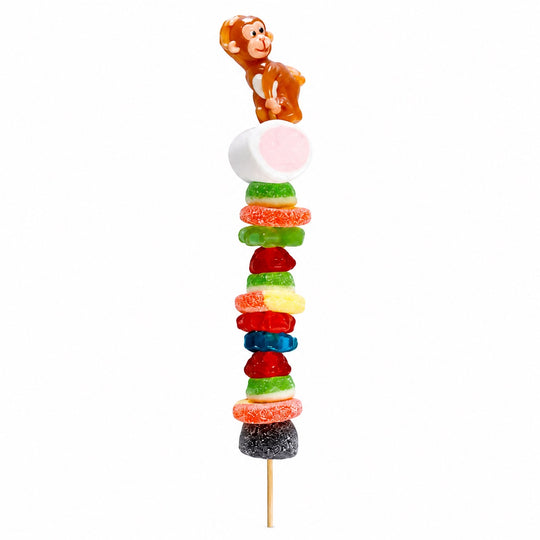 Monkey candy kabob featuring a brown monkey candy topper and assorted fruit-flavored candies on a wooden skewer, isolated on a white background.