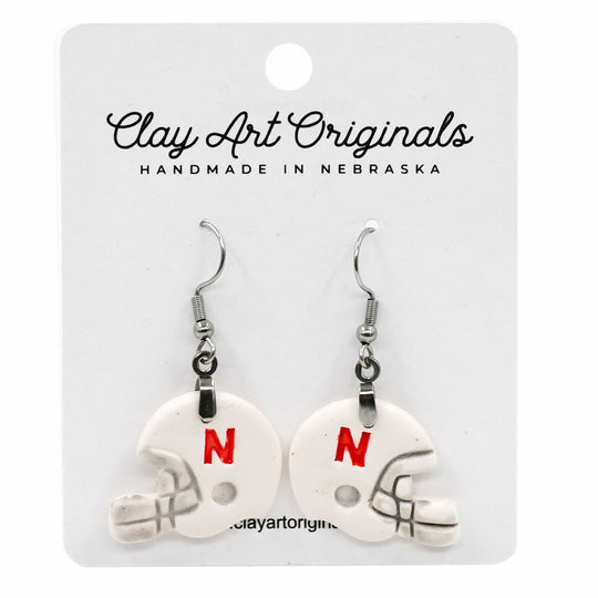 Pair of white helmet-shaped earrings with red 'N' on a Clay Art Originals card.
