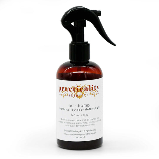 A 240 mL amber glass spray bottle of Practicality Skincare 'No Chomp' botanical outdoor defense oil, featuring a black trigger sprayer and a white label with gold and red text, set against a plain white background.