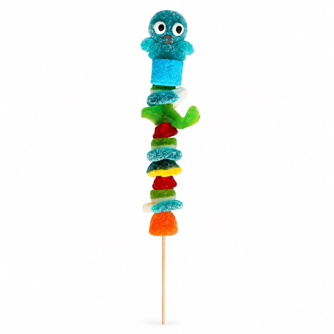 Octopus candy kabob topped with a blue octopus gummy and stacked with assorted gummy candies on a wooden skewer, isolated on a white background.