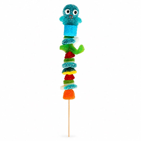 Octopus candy kabob topped with a blue octopus gummy and stacked with assorted gummy candies on a wooden skewer, isolated on a white background.