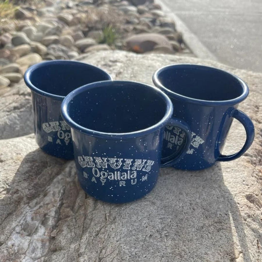 Three Ogallala Bay Rum blue and white mugs on a rock