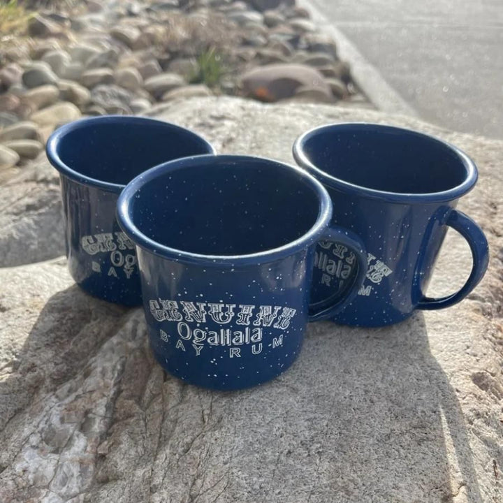 Three Ogallala Bay Rum blue and white mugs on a rock